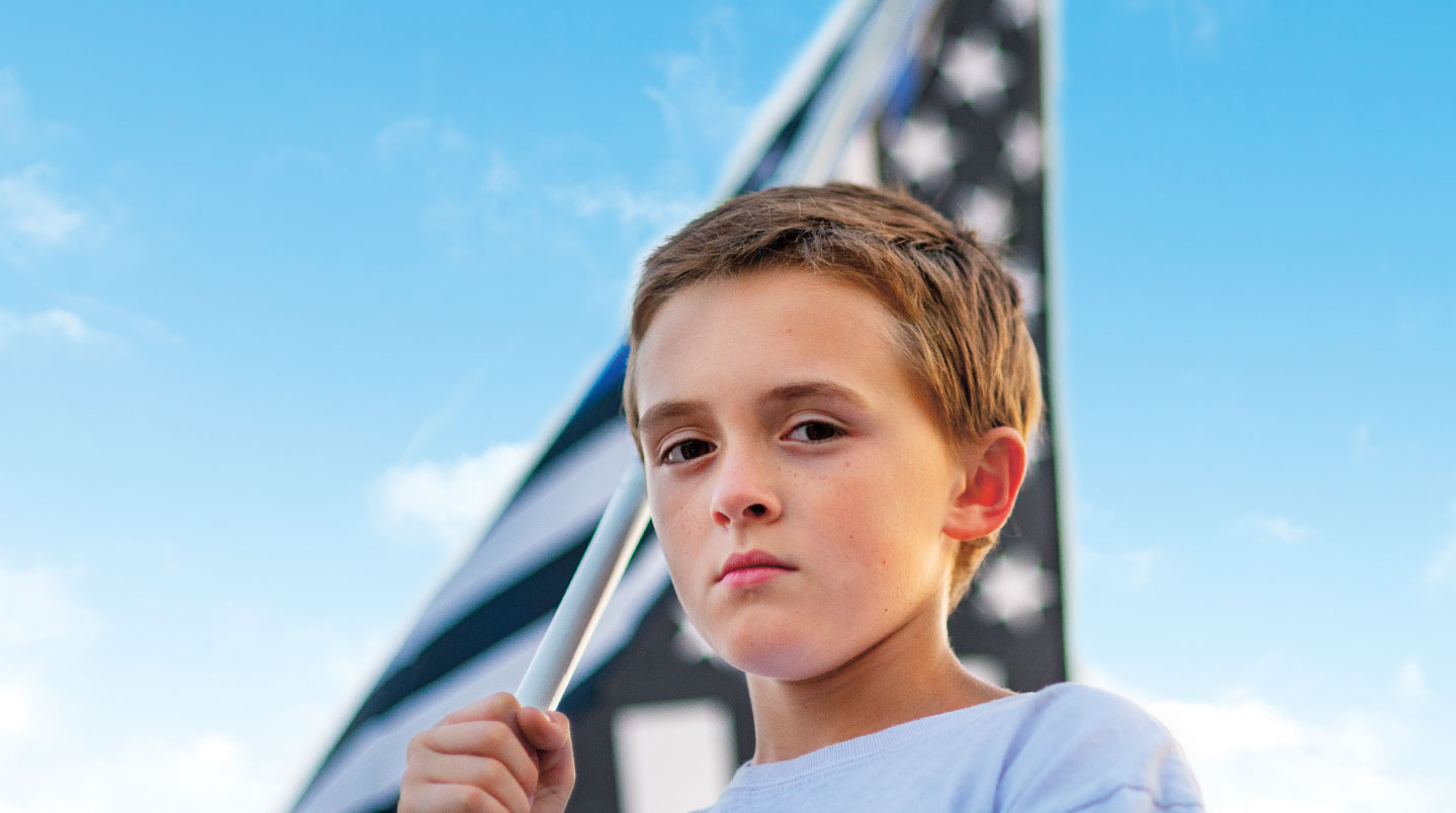 A young boy carries a flag.