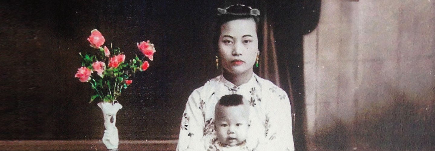 A woman in traditional clothing holds her child in her lap.