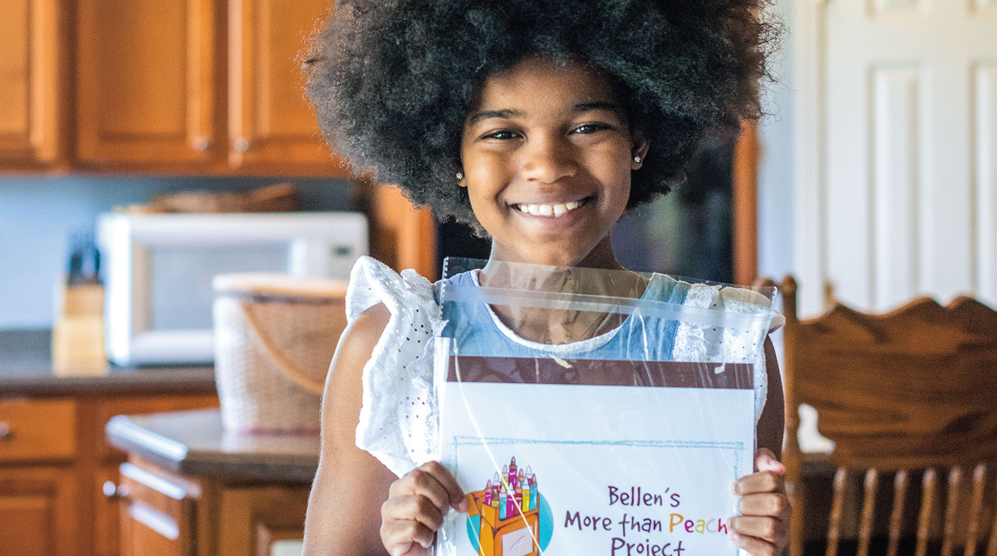 Bellen smiles while holding a More than Peach Project package