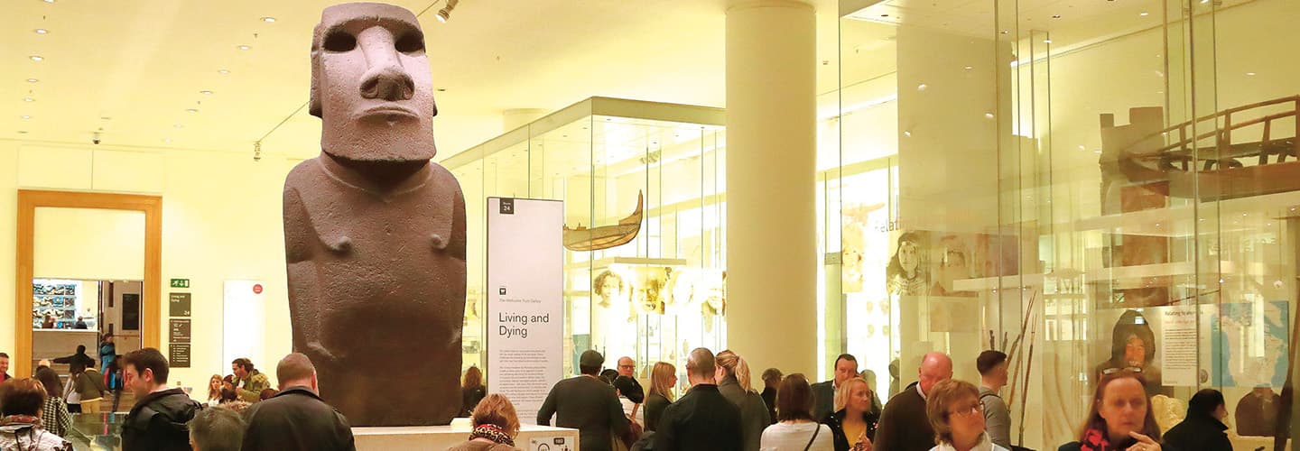 a crowd gathers at a museum to look at a stone statue